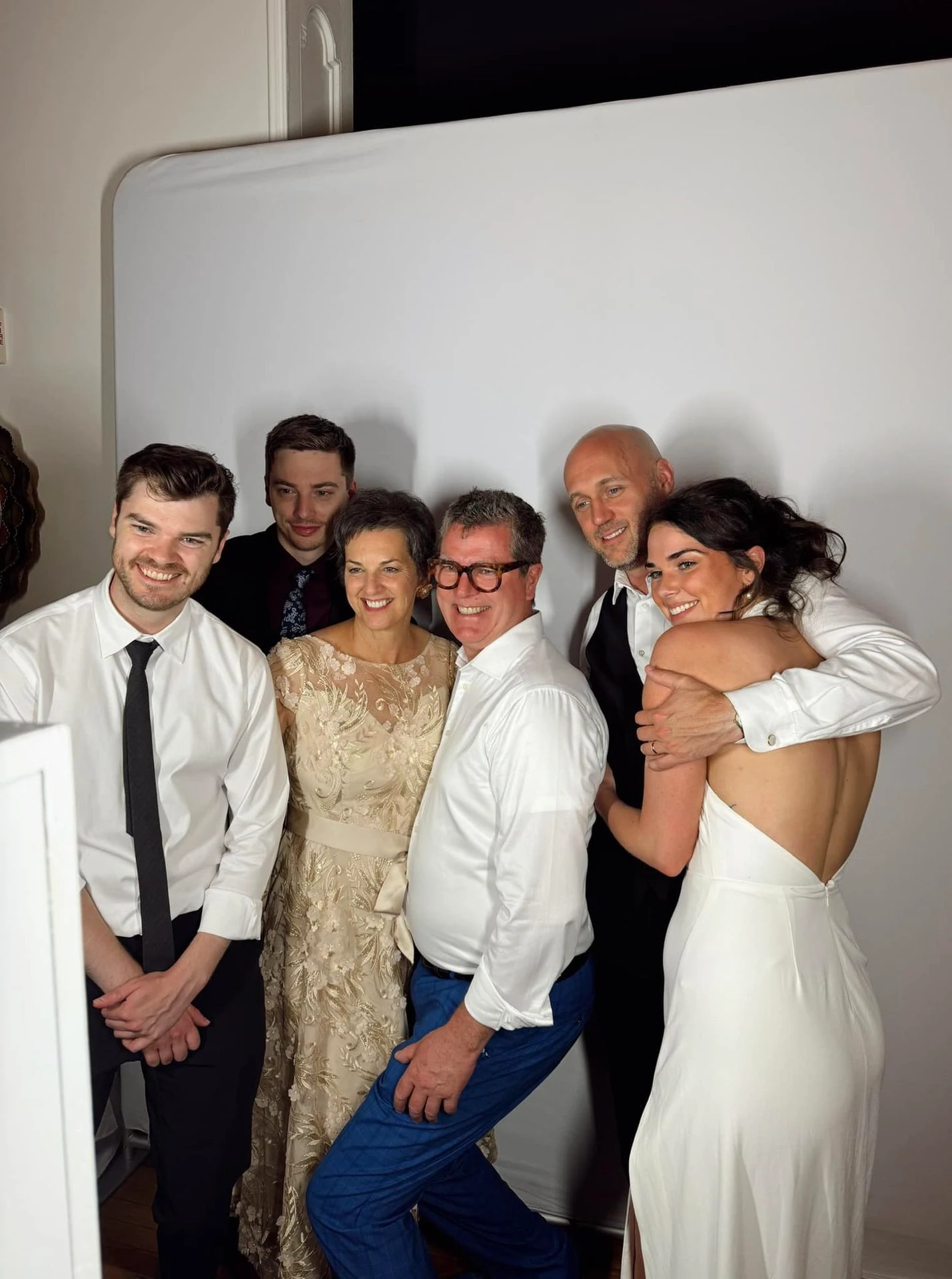 Bride and groom posing with guests in front of photo booth backdrop during Halifax wedding reception